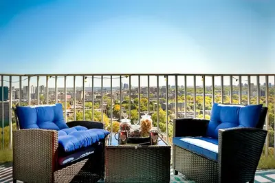 a balcony with two chairs and a dog on a table at Beautiful APARTMENT - GORGEOUS VIEW of the city - 7 MINUTE WALK TO METRO - SELF CHECK IN in Montréal