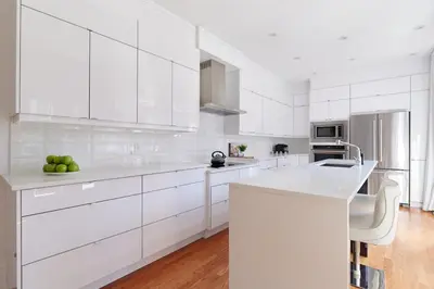 a white kitchen with white cabinets and a counter at Villa Dante By Denstays in Montréal