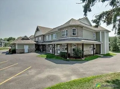 a large house with a parking lot in front of it at Condo-hôtel Le Champlain - Condo103 Bromont in Bromont