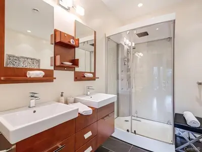 a bathroom with a shower and two sinks and a glass shower stall at Condo-hôtel Le Champlain - Condo103 Bromont in Bromont