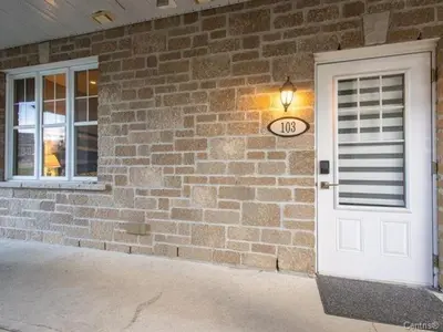 a brick building with a door and a clock on it at Condo-hôtel Le Champlain - Condo103 Bromont in Bromont