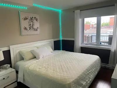 a bedroom with a bed and a window with blue lights at Sunset Apartment in Montréal