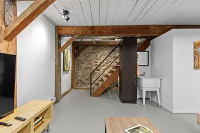 a room with a staircase and a table and a desk at L'Artisan - Vieux-Terrebonne in Terrebonne