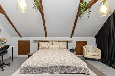a bedroom with a bed and a chair at L'Artisan - Vieux-Terrebonne in Terrebonne
