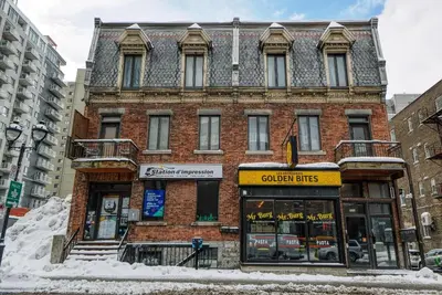 a brick building on a street with snow in front at Studio Stays Downtown Montreal in Montréal