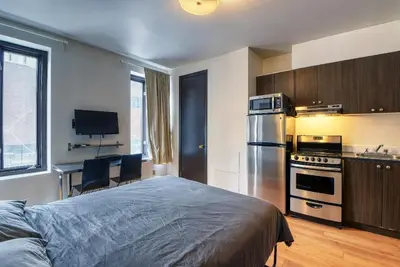 a bedroom with a bed and a kitchen with a refrigerator at Studio Stays Downtown Montreal in Montréal