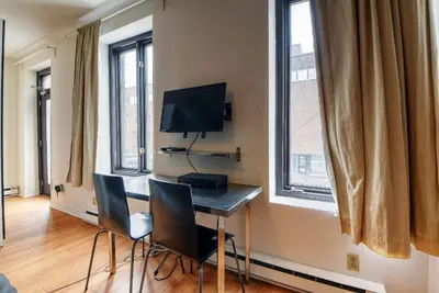 a room with a desk with chairs and a television at Studio Stays Downtown Montreal in Montréal