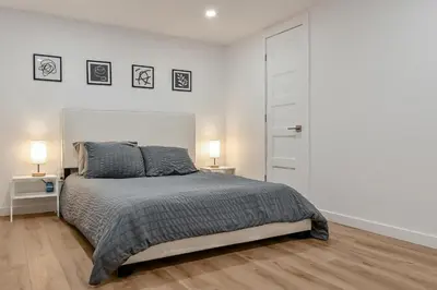 a white bedroom with a bed and two lamps at Le Eleven 55 - Billard - 5 lits in Trois-Rivières
