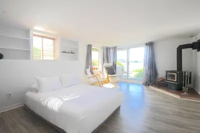 a white bedroom with a bed and a fireplace at Le Vacancier sur le lac in Saint Denis de Brompton
