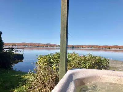 a bath tub sitting next to a body of water at Le Vacancier sur le lac in Saint Denis de Brompton