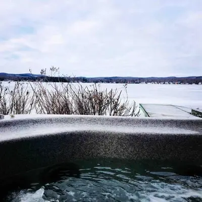a bath tub with snow on it next to a body of water at Le Vacancier sur le lac in Saint Denis de Brompton