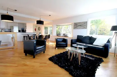 a living room with a black couch and chairs at Le Vacancier sur le lac in Saint Denis de Brompton