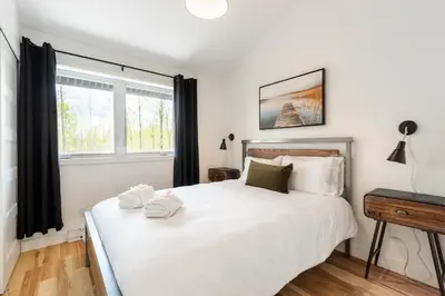 a bedroom with a white bed with two towels on it at Le Memph Hirondelle spacious comfortable condo cottage eco responsible 3 bedrooms - hot tub & pool Memphrémagog Lake in Magog-Orford