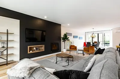 a living room with a gray couch and a black wall at Le Memph Hirondelle spacious comfortable condo cottage eco responsible 3 bedrooms - hot tub & pool Memphrémagog Lake in Magog-Orford