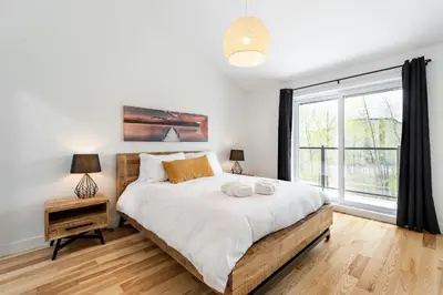 a bedroom with a bed and a large window at Le Memph Hirondelle spacious comfortable condo cottage eco responsible 3 bedrooms - hot tub & pool Memphrémagog Lake in Magog-Orford