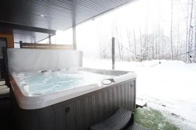 a jacuzzi tub in a room with a snow covered window at Le Memph Hirondelle spacious comfortable condo cottage eco responsible 3 bedrooms - hot tub & pool Memphrémagog Lake in Magog-Orford