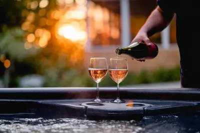 a person pouring wine into two glasses on a table at Chalet Memphrémagog Ski Spa, Étang in Mansonville