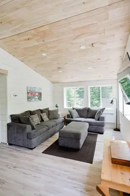 a living room with two couches and a table at Chalet Memphrémagog Ski Spa, Étang in Mansonville