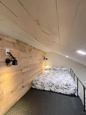 a bed in a room with a wooden wall at Chalet Memphrémagog Ski Spa, Étang in Mansonville