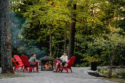 a group of people sitting around a fire in a park at Chalet Memphrémagog Ski Spa, Étang in Mansonville