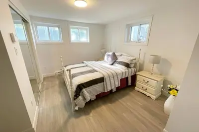 a small bedroom with a bed and a night stand at Stylish and luxurious apartment basement unit in Longueuil