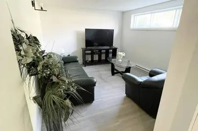 a living room with two couches and a tv at Stylish and luxurious apartment basement unit in Longueuil