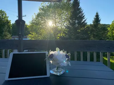 a laptop sitting on a table with a vase of flowers at Relaxez, condo Zen, climatisé, campagne&lacs in Magog-Orford