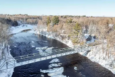 a bridge over a river with snow on the ground at Le Perché-sur-la-rivière in Joliette
