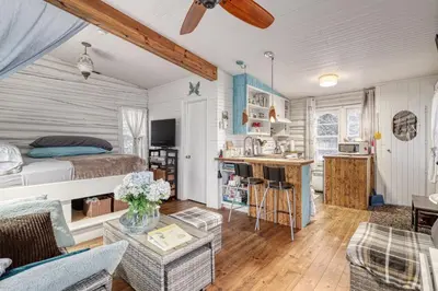 a bedroom and living room with a bed and a kitchen at Le Perché-sur-la-rivière in Joliette