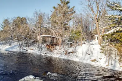 a cabin in the snow next to a river at Le Perché-sur-la-rivière in Joliette
