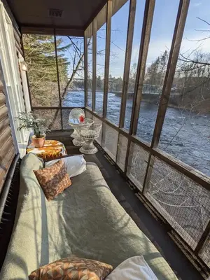 a screened in porch with a view of the water at Le Perché-sur-la-rivière in Joliette