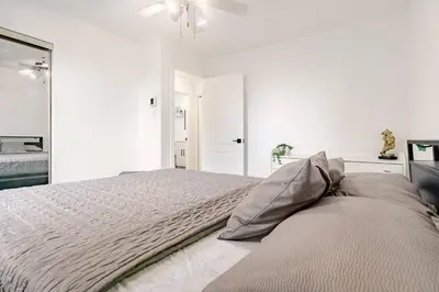 a white bedroom with a bed and a ceiling fan at Top Rated Vacation House Montreal Private Parking in Laval