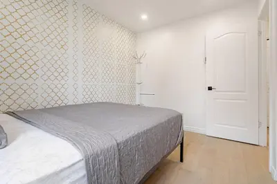 a bedroom with a bed and a white wall at Top Rated Vacation House Montreal Private Parking in Laval