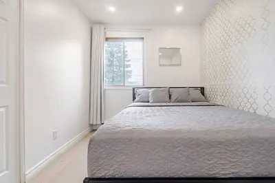 a bed in a white room with a window at Top Rated Vacation House Montreal Private Parking in Laval