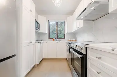 a white kitchen with white cabinets and a window at Top Rated Vacation House Montreal Private Parking in Laval