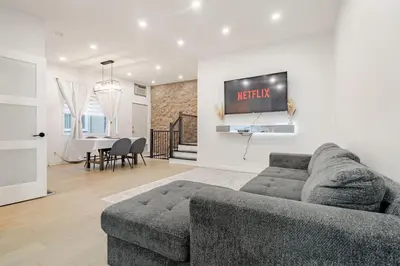 a living room with a couch and a tv on a wall at Top Rated Vacation House Montreal Private Parking in Laval