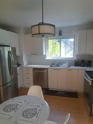 a kitchen with white cabinets and a table and a window at Confort in Montréal