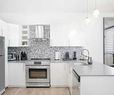 a kitchen with white cabinets and a stainless steel oven at Chic 1-Bedroom Retreat in Montreal's Vibrant Plateau Mont-Royal Area - Apt 3 in Montréal