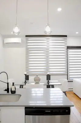 a kitchen with white counters and a sink and two windows at Chic 1-Bedroom Retreat in Montreal's Vibrant Plateau Mont-Royal Area - Apt 3 in Montréal
