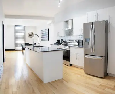 a kitchen with white cabinets and a stainless steel refrigerator at Eat, Explore & Enjoy Downtown Montreal at this Sleek City Escape located in Plateau Mont-Royal - Apt 4 in Montréal