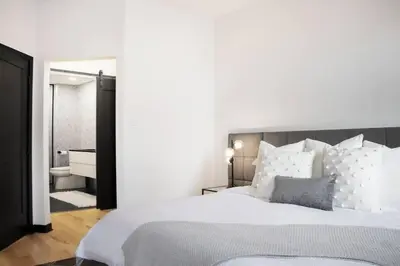 a bedroom with a large white bed and a bathroom at Upscale 3-Bedroom Entire Unit in the Trendy Plateau Mont-Royal featuring A Magazine-Worthy Kitchen & Opulent Living Spaces - Apt 1 in Montréal
