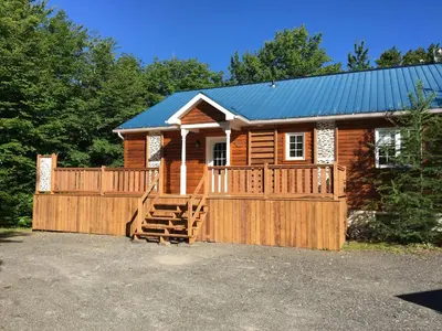 a log cabin with a wooden fence and a porch at Domaine des Montagnais in Notre-Dame-Des-Bois