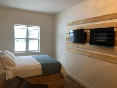 a bedroom with a bed and a tv on a wall at Domaine des Montagnais in Notre-Dame-Des-Bois