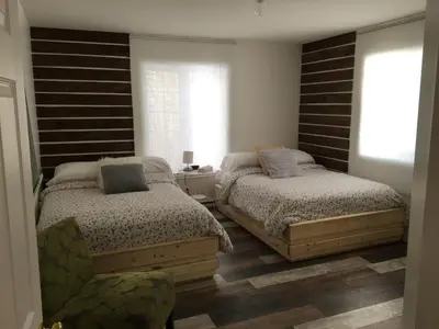 a bedroom with two beds and a chair at Domaine des Montagnais in Notre-Dame-Des-Bois