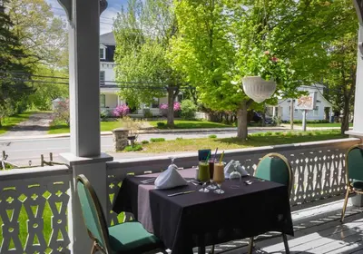 a table on a porch with a view of a street at Auberge Lakeview Inn in Lac-Brome