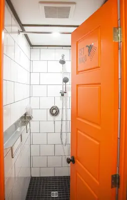 an orange door in a bathroom with a shower at Le Bed & Cocktail - Appartement sur l'Avenue du Mont-Royal in Montréal
