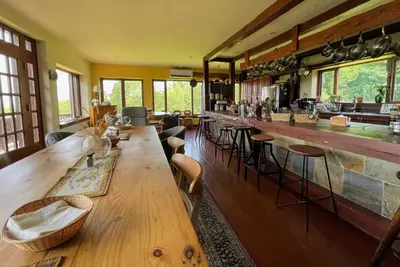 a restaurant with a long wooden table and a bar at Sugar Hill Retreat #296692 in Lac-Brome