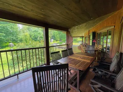 a screened in porch with a wooden table and chairs at Sugar Hill Retreat #296692 in Lac-Brome