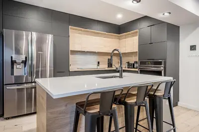 a kitchen with a sink and a counter with bar stools at FREE PARKING PRIME LOCATION NEW MODERN CONDO in Brossard