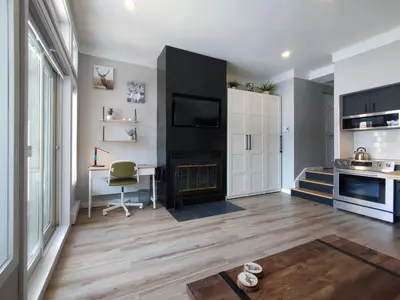 a living room with a fireplace and a desk at Chalet Détente Orford in Orford